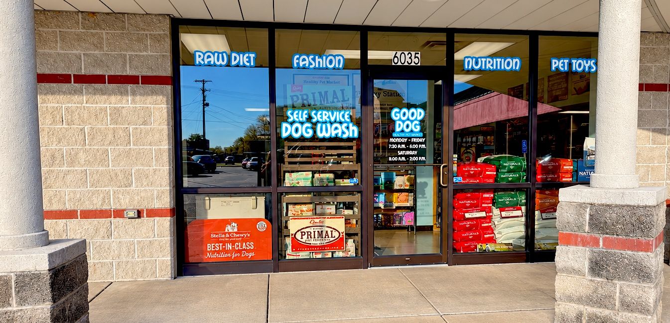 The Good Dog Healthy Pet Market storefront at 6035 N Main Street Rd, with window signs for raw diet, nutrition, pet toys and the self-service dog wash, and store hours on the door.