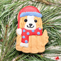 Festive dog-shaped cookie wearing a red Santa hat and scarf