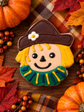 Festive witch-shaped fall cookie with a brown hat and green scarf
